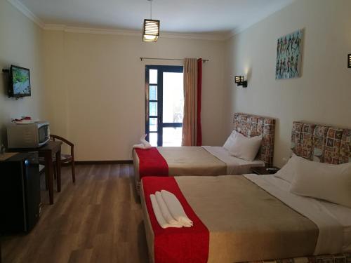 a hotel room with two beds and a tv at Cordoba Suites in Hurghada