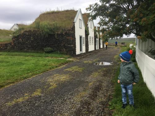 a young boy standing on a dirt road next to a house at Öndólfsstaðir Farm B&B in Laugar
