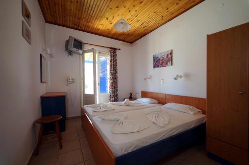 1 dormitorio con cama con sábanas blancas y techo de madera en White Rock Apartments, en Marathokampos
