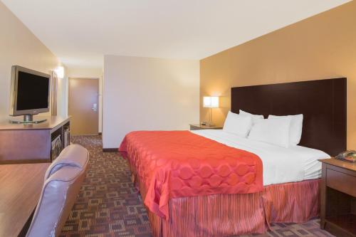 a hotel room with a bed and a flat screen tv at Sky Tree Hotels in Tulsa