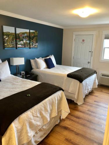 two beds in a room with blue walls at Arnold's Cove Inn in Arnold's Cove