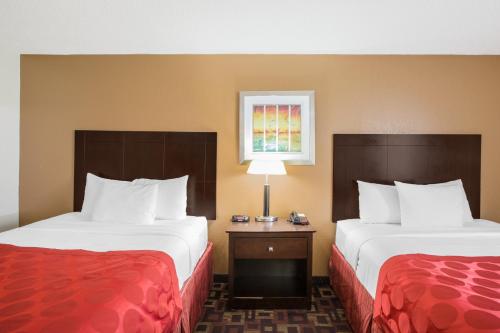 a hotel room with two beds and a table with a lamp at Sky Tree Hotels in Tulsa
