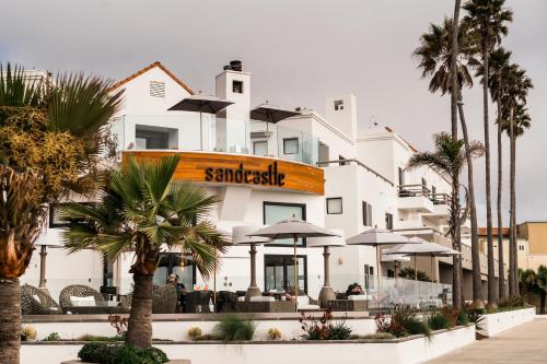 a white building with palm trees in front of it at Sandcastle Hotel on the Beach in Pismo Beach
