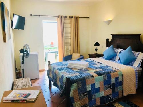 Un dormitorio con una cama con almohadas azules y una mesa. en Bella & Gordinho GuestHouse, en Lagos