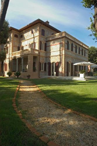 a large stone building with a grassy yard at Villa Signori in Marina di Pietrasanta
