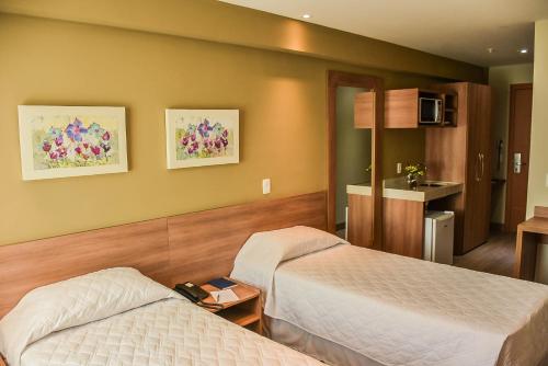 a hotel room with two beds and a kitchen at Mont Blanc Suites Duque de Caxias in Duque de Caxias