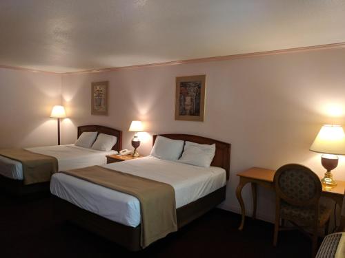 two beds in a hotel room with two lamps at Saddle West Casino Hotel in Pahrump