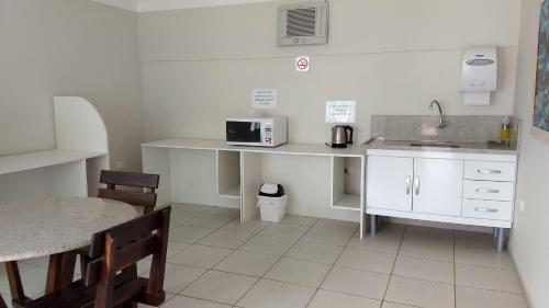 uma cozinha com uma mesa, um lavatório e um micro-ondas em Hotel Santa Paula em Guaratuba