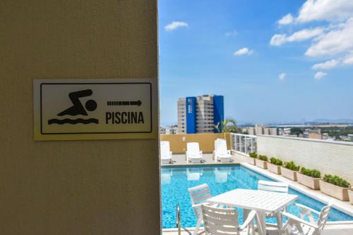 a sign on a wall next to a swimming pool at Mont Blanc Suites Duque de Caxias in Duque de Caxias