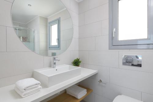 a white bathroom with a sink and a mirror at Villa Hermes with pool & jacuzzi in Lindos in Líndos