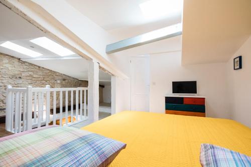 ペリグーにあるPetit studio Saint-Front- Small studio flat Saint-Frontのベッドルーム(黄色いベッド1台、テレビ付)