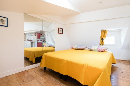 a bedroom with two beds with yellow sheets at Petit studio Saint-Front- Small studio flat Saint-Front in Périgueux