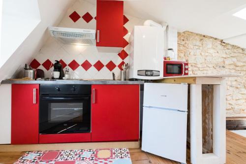 a kitchen with red cabinets and a white refrigerator at Petit studio Saint-Front- Small studio flat Saint-Front in Périgueux