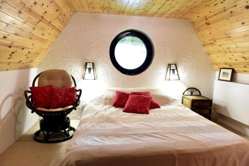 a bedroom with a bed with a round window and a chair at Leśna Strzecha Domek in Rotembark