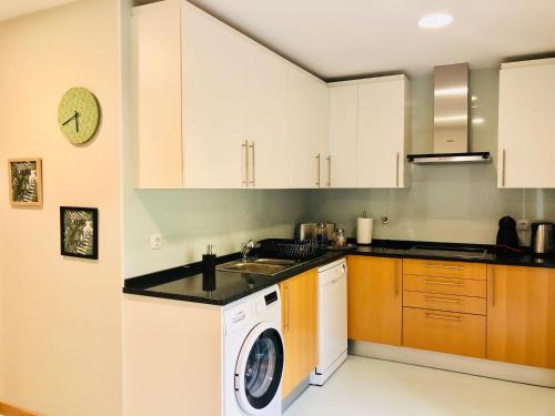 a kitchen with white cabinets and a washing machine at Mar Alto,in Marina Village in Olhão