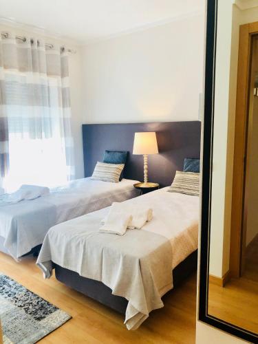 two beds in a room with a mirror at Mar Alto,in Marina Village in Olhão