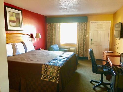 a hotel room with a bed and a desk and a window at Lone Star Inn in Lubbock