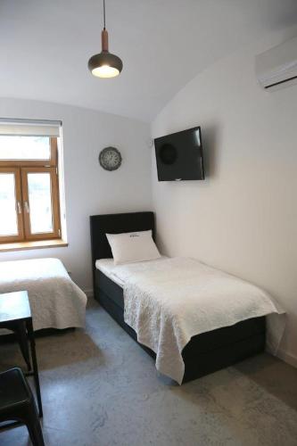a bedroom with two beds and a tv on the wall at Aparthotel Zakątna B&B in Tarnów