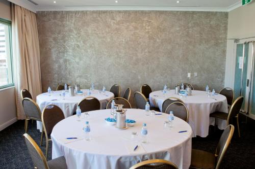a room with tables and chairs with white table cloths at The Sebel Sydney Chatswood in Sydney