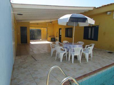 eine Terrasse mit Tisch und Stühlen und einem Sonnenschirm in der Unterkunft Casa c/ Piscina - Ampla e Arejada Balneário Gaivota - 300 mts da Praia in Itanhaém