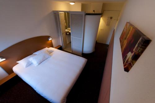 a small bedroom with a white bed in a room at Quick Palace Pau Zénith in Pau
