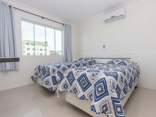 2 camas en un dormitorio blanco con ventana en Aruba en Bombinhas