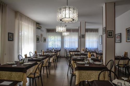 un comedor con mesas y sillas y una lámpara de araña en Hotel Zani en Cervia