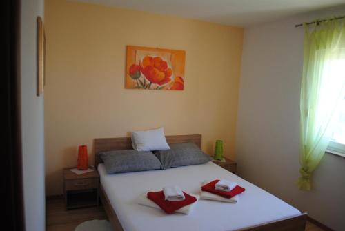 1 dormitorio con 1 cama con 2 almohadas rojas en Apartments Vidolma en Povljana