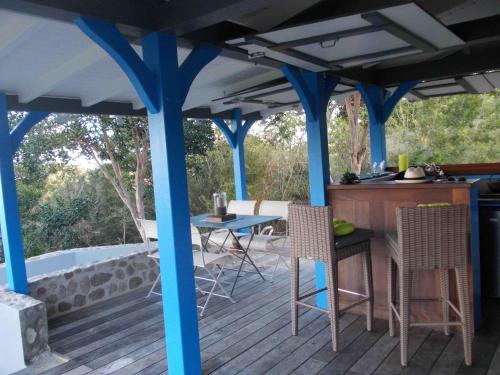 une terrasse avec colonnes bleues, table et chaises dans l'établissement Les Hauts de la Baie, à Terre-de-Bas