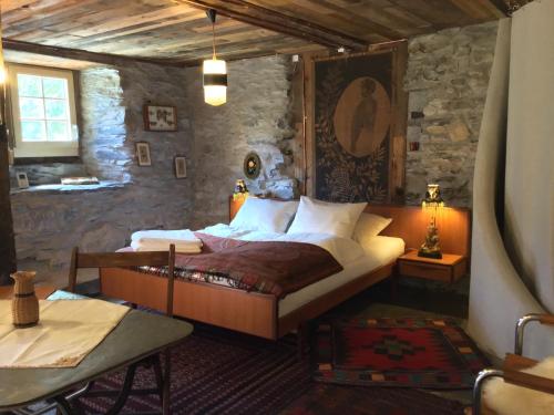 - une chambre avec un lit et un mur en pierre dans l'établissement Lieu Secret dans les Alpes Suisses, à Le Trétien