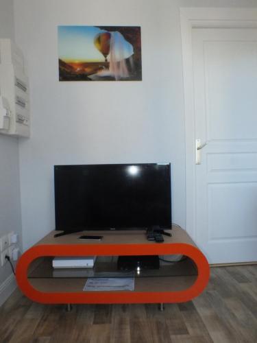 an orange coffee table with a flat screen tv on it at Residence Miranto in Châteauroux