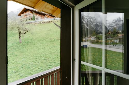 a window with a view of a green field at Amazing Apartment EIGER Grindelwald in Grindelwald