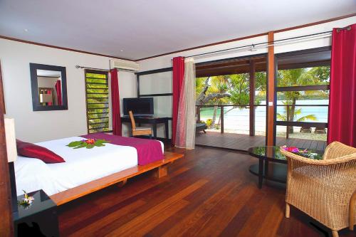 Oure Lodge Beach Resort في Vao: غرفة نوم بسرير ومكتب ونافذة