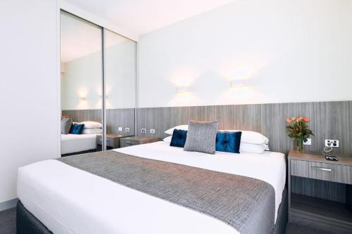 a bedroom with a large white bed with blue pillows at Club Laverton in Laverton