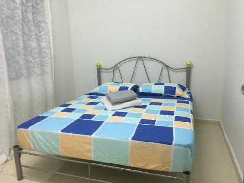 ein Schlafzimmer mit einem Bett mit einer blauen und gelben Decke in der Unterkunft Taman Rambai Utama Homestay in Malakka