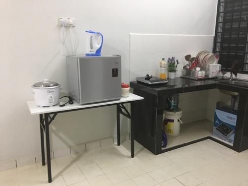 a kitchen with a counter and a table with a microwave at Taman Rambai Utama Homestay in Malacca