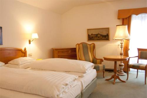 a hotel room with two beds and a table and chairs at Hotel Landhaus Fuhrgassl-Huber in Vienna