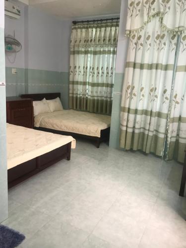 a room with two beds and a window with curtains at Minh Ha Hotel in La Gi