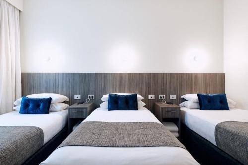 two beds in a hotel room with blue pillows at Club Laverton in Laverton