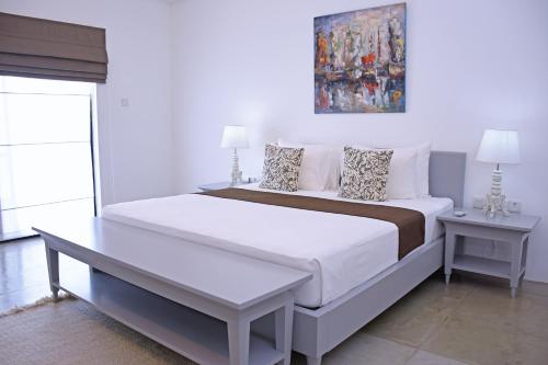 a white bedroom with a large bed and two tables at Villa Santé by The Serendipity Collection in Kalpitiya