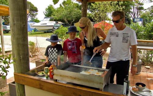 a man and a woman and two children standing in front of a table at Pohara Beach TOP 10 Holiday Park in Pohara