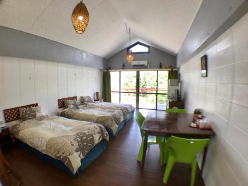 Duas camas num quarto com uma mesa e um estofado de esteira de mesa em Surfside Bed & Breakfast em Onna