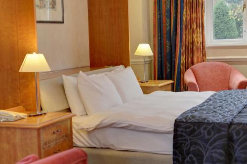 a hotel room with a bed and two chairs at Quorn Country Hotel Leicester in Loughborough