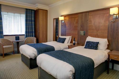 a hotel room with two beds and a table at Quorn Country Hotel Leicester in Loughborough