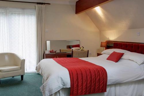 a bedroom with a large bed with a red blanket at The Cedars Hotel in Stowmarket
