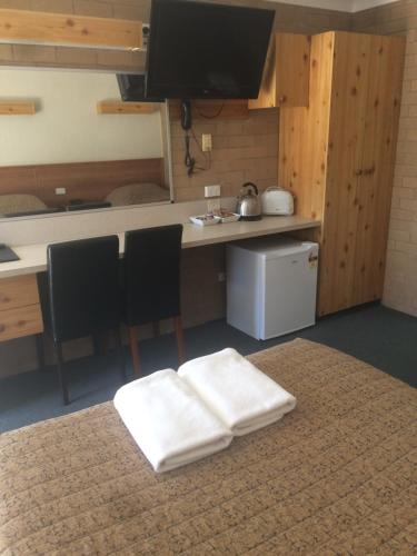 a room with a kitchen and a table with two white towels at Alexander Motor Inn in Moree