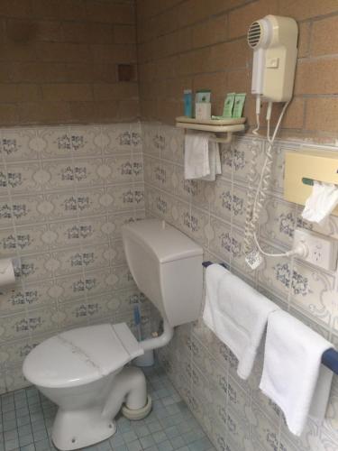 a bathroom with a toilet and a phone on the wall at Alexander Motor Inn in Moree