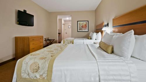 a hotel room with two beds and a television at Best Western Plus Chateau Inn Sylvan Lake in Sylvan Lake