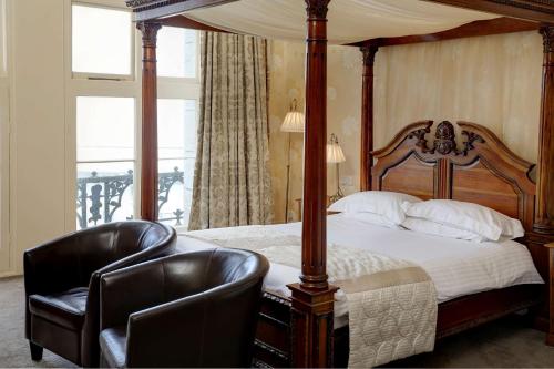 a bedroom with a canopy bed and two leather chairs at Duke Of Cornwall Hotel in Plymouth