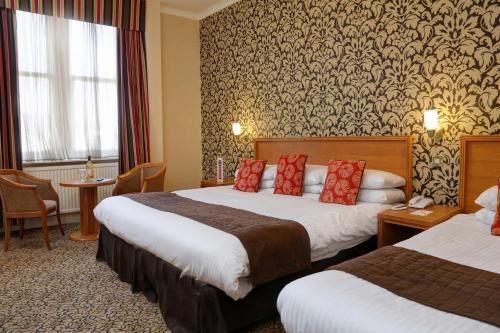 ein Hotelzimmer mit 2 Betten und roten Kissen in der Unterkunft Best Western Queens Hotel in Dundee